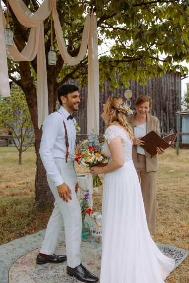 Brautpaar blickt sich verliebt an unter freiem Himmel, Rednerin steht daneben